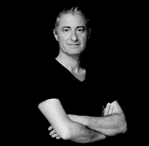 Black-and-white headshot of Alexandre facing the camera with his arms crossed